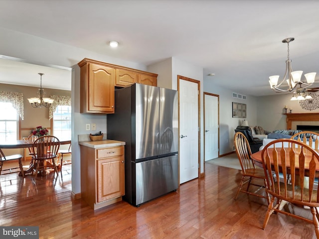 kitchen featuring decorative light fixtures, dark hardwood / wood-style floors, stainless steel refrigerator, and an inviting chandelier