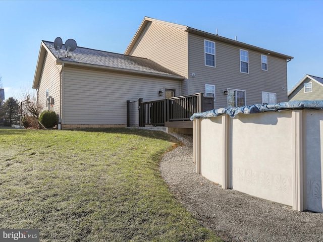 rear view of property featuring a lawn and a wooden deck