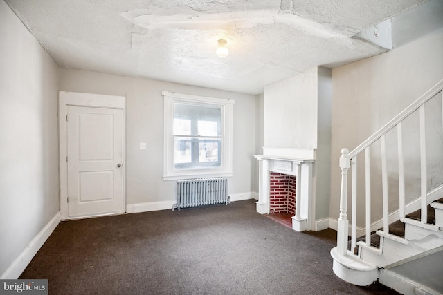 unfurnished living room featuring radiator heating unit, dark carpet, and a textured ceiling