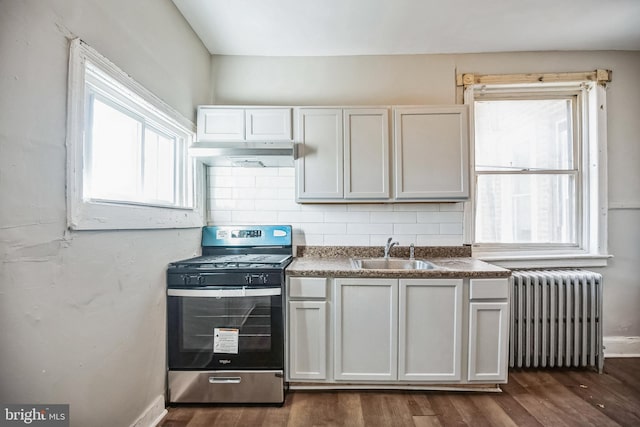 kitchen featuring stainless steel gas range oven, sink, radiator heating unit, dark hardwood / wood-style floors, and white cabinetry