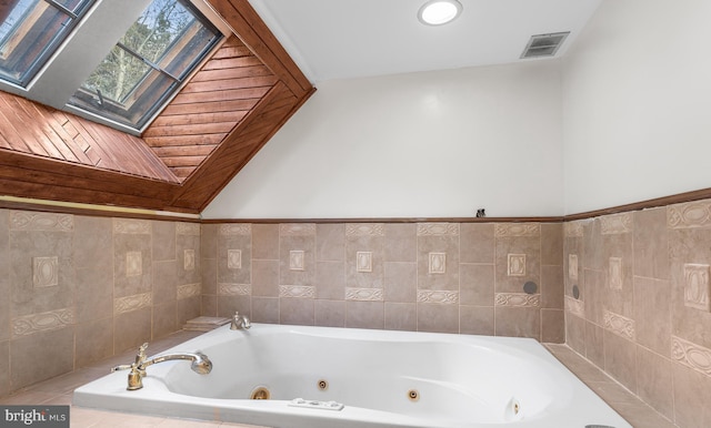 bathroom featuring a skylight and tiled tub