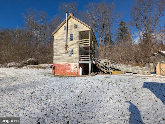 snow covered back of property with a balcony