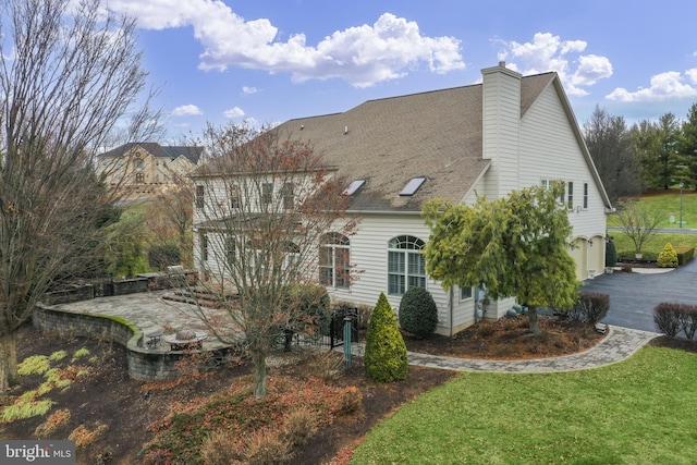 exterior space featuring a garage, a patio, and a lawn