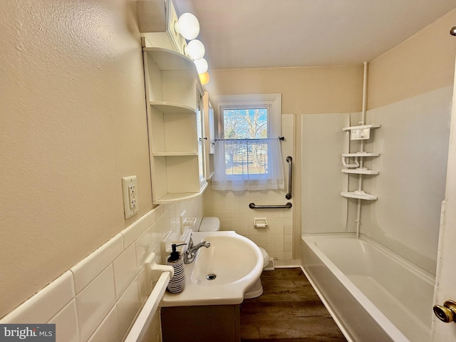 bathroom with hardwood / wood-style floors, bathing tub / shower combination, tile walls, and sink