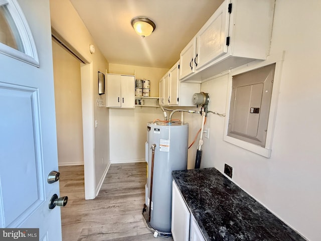 clothes washing area featuring electric panel, light hardwood / wood-style floors, and water heater