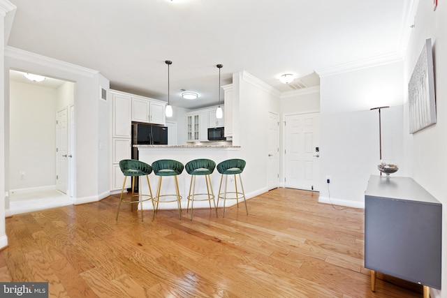 kitchen with black appliances, crown molding, kitchen peninsula, light wood-type flooring, and white cabinetry