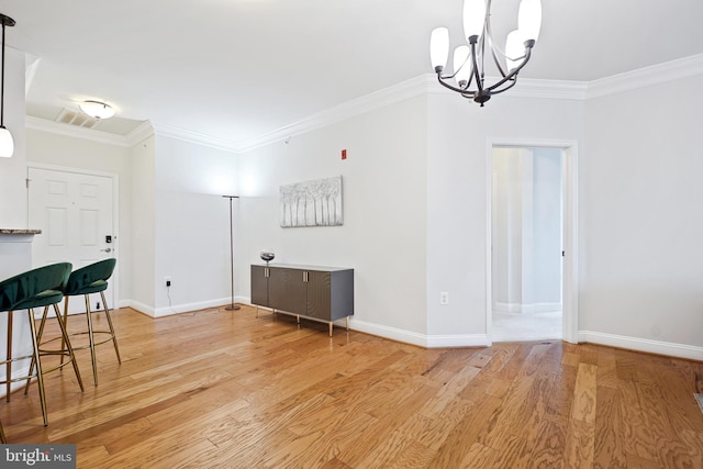 dining area featuring light wood-type flooring, crown molding, and a notable chandelier