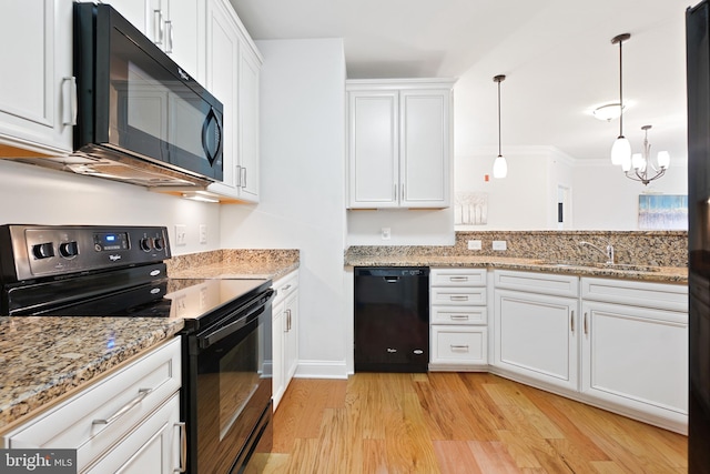 kitchen with white cabinets, decorative light fixtures, light hardwood / wood-style flooring, and black appliances