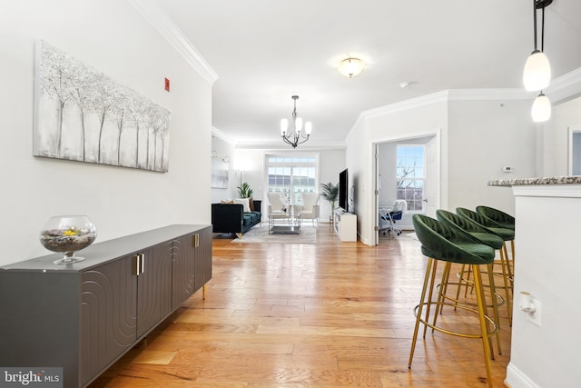 corridor featuring a chandelier, light wood-type flooring, and crown molding