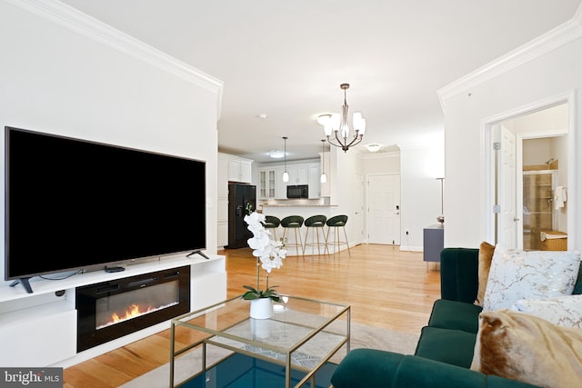 living room with crown molding, light hardwood / wood-style flooring, and an inviting chandelier