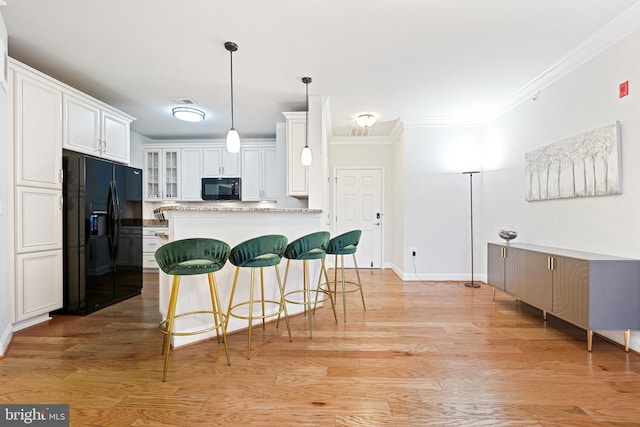 kitchen featuring white cabinets, light hardwood / wood-style flooring, ornamental molding, and black appliances