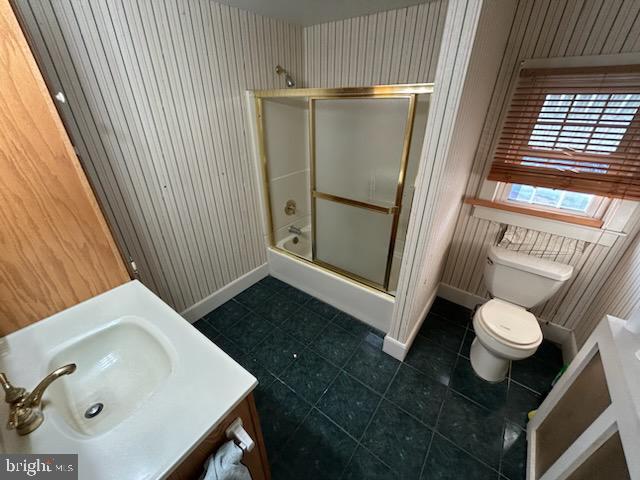 full bathroom with tile patterned floors, wood walls, and toilet