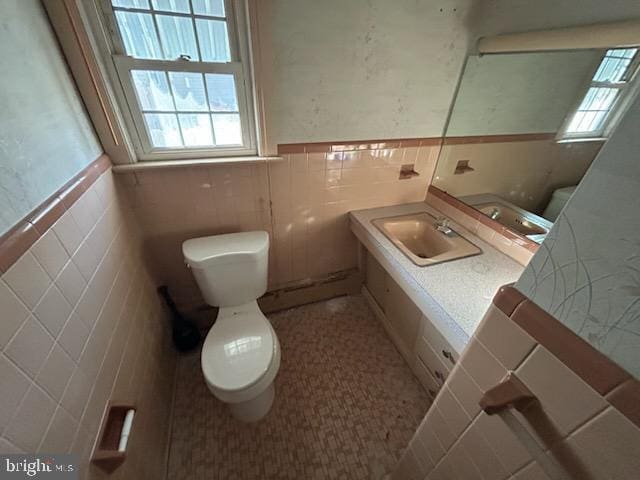 bathroom featuring vanity, tile walls, and toilet