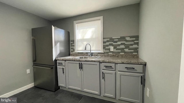 kitchen featuring decorative backsplash, sink, dark tile patterned flooring, white cabinetry, and stainless steel refrigerator