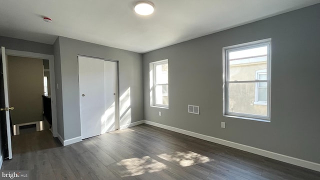 unfurnished bedroom with dark hardwood / wood-style floors and a closet