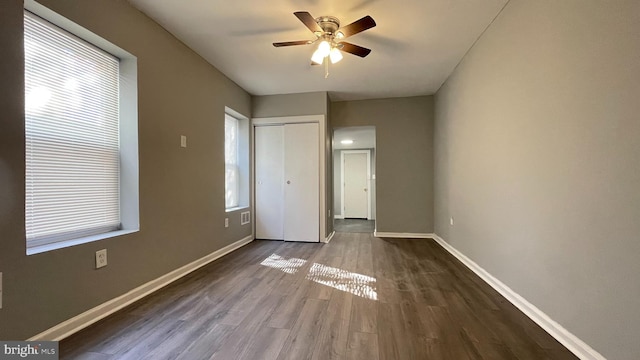 unfurnished bedroom featuring ceiling fan, a closet, and dark wood-type flooring