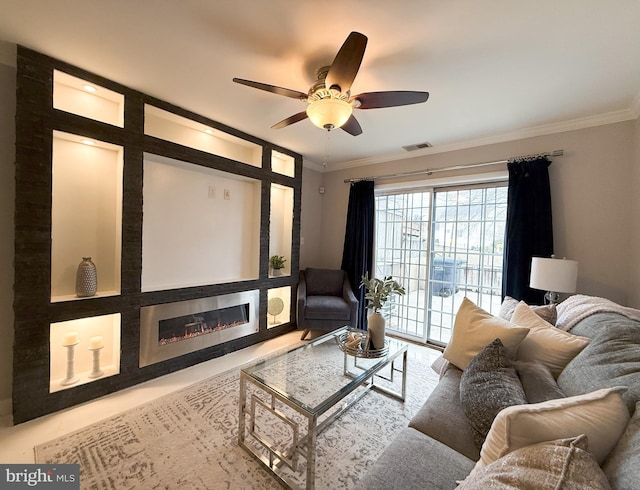 living room featuring a large fireplace, ceiling fan, and crown molding