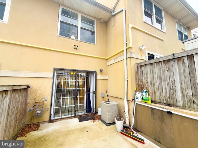 view of exterior entry featuring a patio area and central AC unit