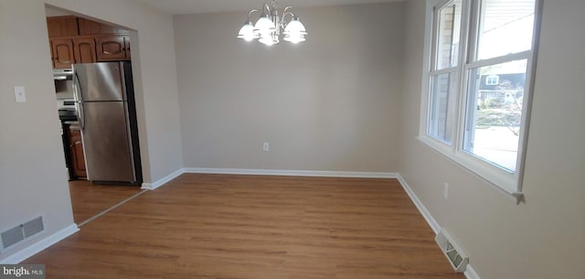 unfurnished dining area featuring a notable chandelier and light hardwood / wood-style floors