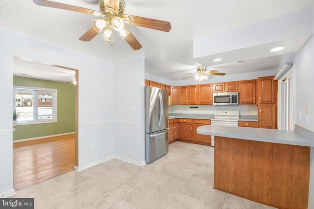 kitchen with ceiling fan, appliances with stainless steel finishes, kitchen peninsula, and backsplash