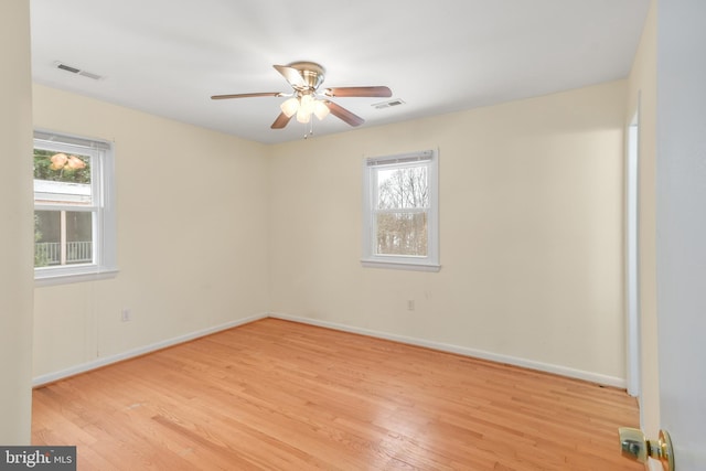 empty room featuring ceiling fan, a healthy amount of sunlight, and light hardwood / wood-style flooring