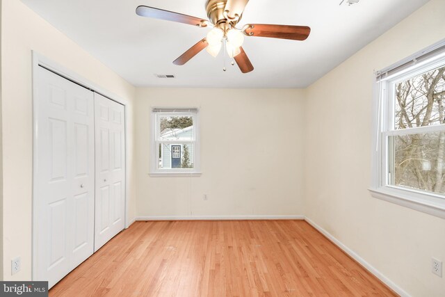 unfurnished bedroom with ceiling fan, light wood-type flooring, and a closet