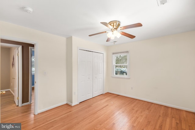 unfurnished bedroom with light wood-type flooring, ceiling fan, and a closet