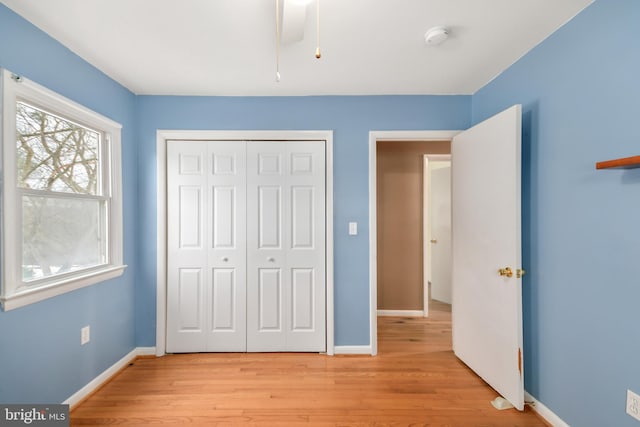 unfurnished bedroom featuring light wood-type flooring, ceiling fan, and a closet