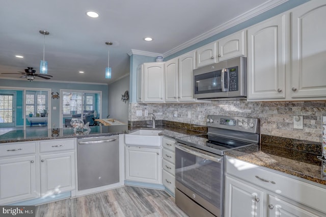 kitchen with white cabinets, decorative light fixtures, sink, and appliances with stainless steel finishes