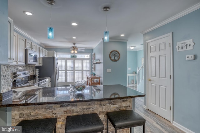 kitchen featuring a breakfast bar, kitchen peninsula, stainless steel appliances, and hanging light fixtures