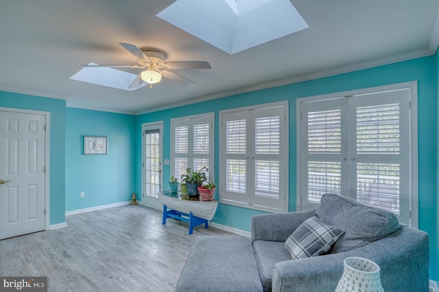 sitting room featuring ceiling fan, a skylight, ornamental molding, and light hardwood / wood-style flooring