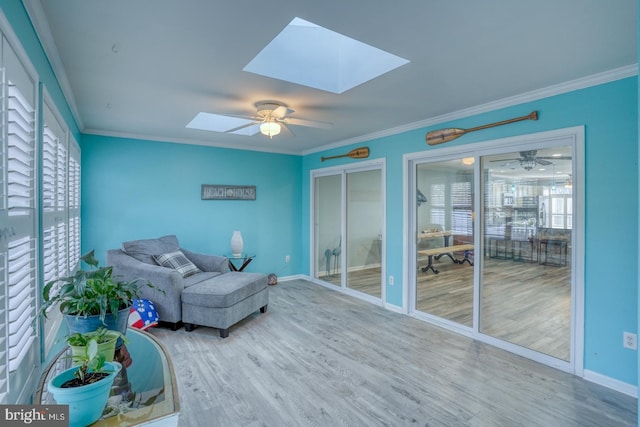 sitting room with a skylight, ceiling fan, crown molding, and hardwood / wood-style flooring