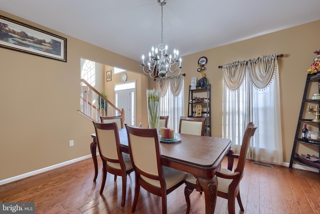 dining area with hardwood / wood-style floors and an inviting chandelier