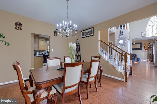 dining area with light wood-type flooring and an inviting chandelier