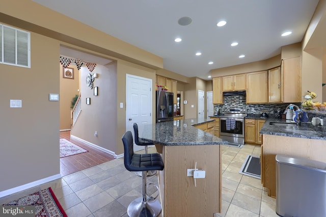 kitchen with light tile patterned flooring, sink, appliances with stainless steel finishes, and dark stone counters