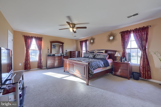 bedroom with ceiling fan, light colored carpet, and multiple windows