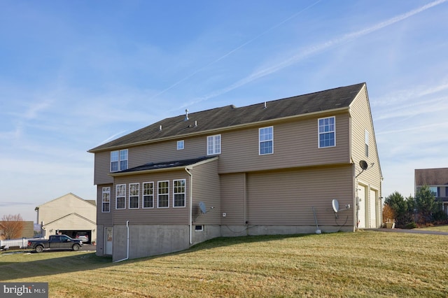 back of property featuring a garage and a yard