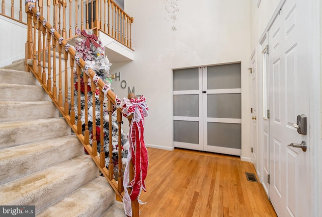 staircase with a high ceiling and hardwood / wood-style flooring