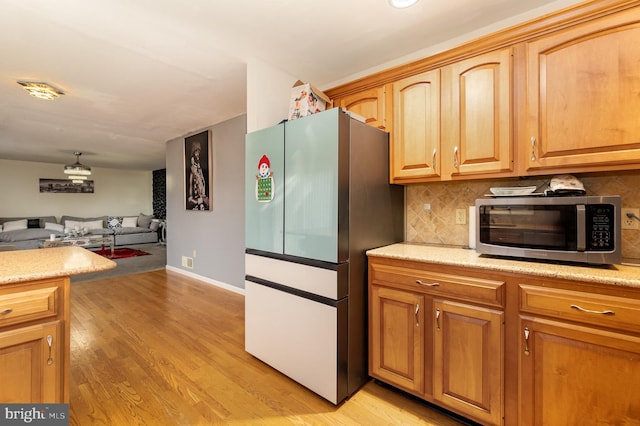 kitchen with decorative backsplash, stainless steel appliances, and light hardwood / wood-style floors