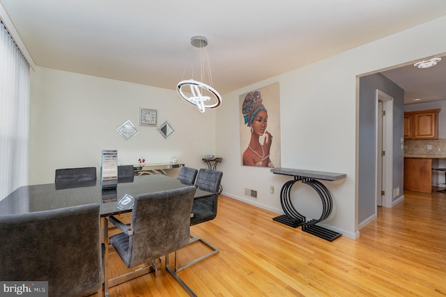 office with light hardwood / wood-style floors and an inviting chandelier