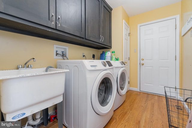 laundry area featuring cabinets, sink, washing machine and dryer, and light hardwood / wood-style flooring