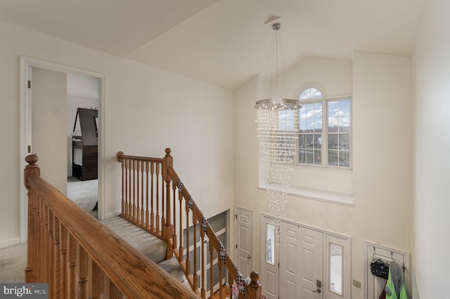 stairs featuring carpet, lofted ceiling, and an inviting chandelier