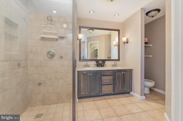 bathroom with tile patterned flooring, vanity, tiled shower, and toilet