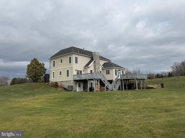 rear view of house featuring a lawn, central air condition unit, and a deck