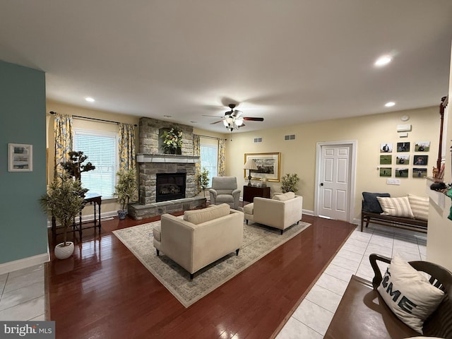 living room featuring a fireplace, ceiling fan, and light hardwood / wood-style flooring