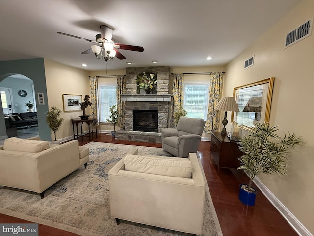 living room featuring ceiling fan, a healthy amount of sunlight, dark hardwood / wood-style flooring, and a fireplace