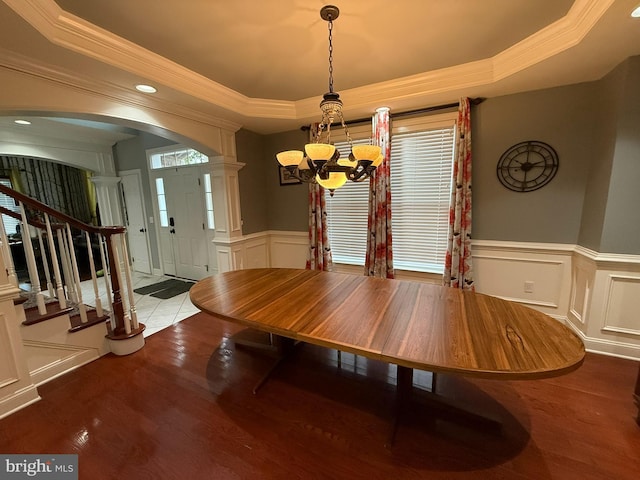 unfurnished dining area featuring a raised ceiling, crown molding, hardwood / wood-style floors, and a chandelier