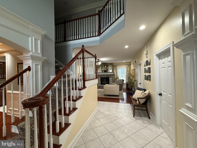 staircase with a fireplace, decorative columns, and tile patterned floors