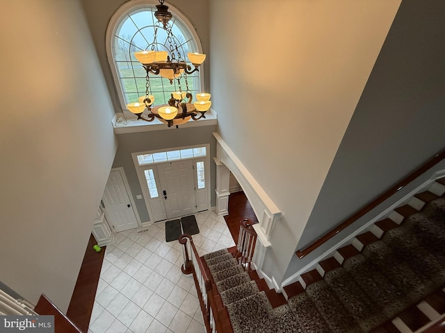 foyer entrance with a notable chandelier, light tile patterned flooring, and a high ceiling