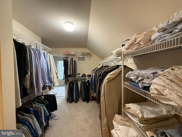 walk in closet with light carpet and vaulted ceiling